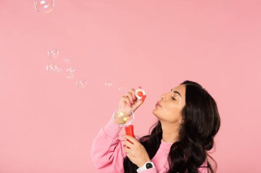 beautiful happy girl blowing soap bubbles isolated on pink clipart