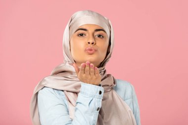 hijab üfleme hava öpücük çekici Müslüman kız portresi, pembe izole