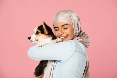 türban mutlu arap kadın galce Corgi köpek yavrusu tutan, pembe izole