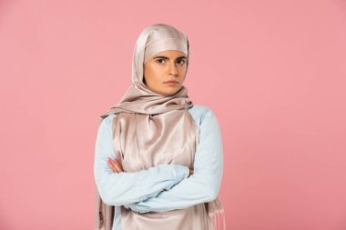 çapraz kolları ile hijab şüpheci İslam kadın, pembe izole 