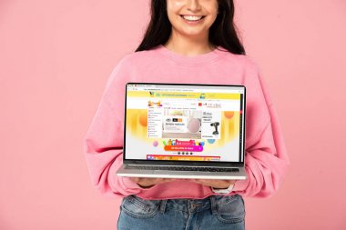 Kiev, Ukrayna - 30 Temmuz 2019: ekranda aliexpress web sitesi ile dizüstü bilgisayar tutan gülümseyen kız kırpılmış görünümü, pembe izole