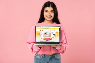 Kiev, Ukrayna - 30 Temmuz 2019: ekranda aliexpress web sitesi ile dizüstü bilgisayar tutan esmer gülümseyen kız, pembe izole