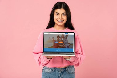 Kiev, Ukrayna - 30 Temmuz 2019: ekranda couchsurfing web sitesi ile dizüstü bilgisayar tutan gülümseyen kız, pembe izole