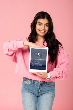 Kiev, Ukrayna - 30 Temmuz 2019: ekranda tumblr uygulaması ile dijital tablet tutan gülümseyen kız, pembe izole