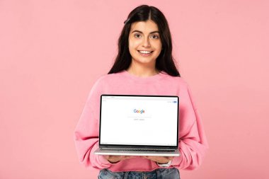Kiev, Ukrayna - 30 Temmuz 2019: ekranda google web sitesi ile dizüstü bilgisayar tutan gülümseyen kız, pembe izole