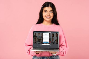 Kiev, Ukrayna - 30 Temmuz 2019: ekranda linkedin web sitesi ile dizüstü bilgisayar tutan gülümseyen kız, pembe izole
