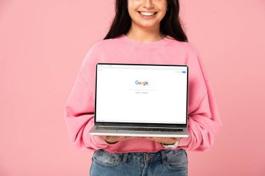 Kiev, Ukrayna - 30 Temmuz 2019: ekranda google web sitesi ile dizüstü bilgisayar tutan gülümseyen kız kırpılmış görünümü, pembe izole