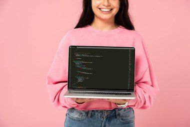 KYIV, UKRAINE - JULY 30, 2019: cropped view of smiling girl holding laptop with html on screen, isolated on pink clipart