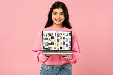 Kiev, Ukrayna - 30 Temmuz 2019: ekranda pinterest web sitesi ile dizüstü bilgisayar tutan gülümseyen kız, pembe izole