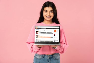Kiev, Ukrayna - 30 Temmuz 2019: ekranda soundcloud web sitesi ile dizüstü bilgisayar tutan gülümseyen kız, pembe izole
