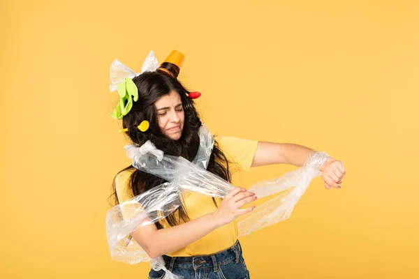 upset young woman with trash in hair isolated on yellow