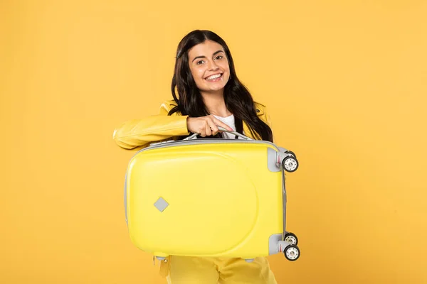 黄色のスーツケースを黄色で隔離した幸せな女性観光客 — ストック写真