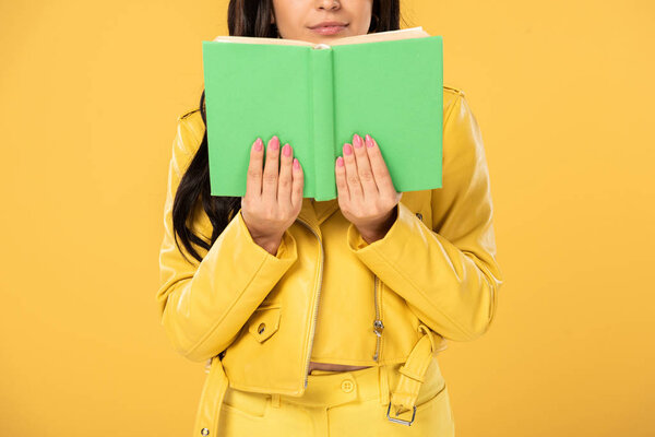 cropped view of student reading book, isolated on yellow 