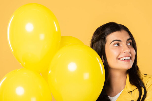 happy girl holding yellow balloons, isolated on yellow