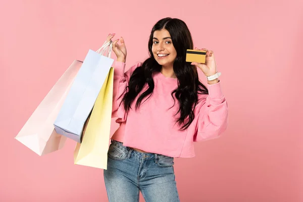 クレジットカードと買い物袋を持つ美しい笑顔の女性 ピンクで孤立 — ストック写真