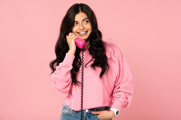 счастливая женщина говорит по ретро-телефону изолированы на розовый
