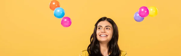 黄色に隔離されたカラフルなボールを持つ幸せな魅力的な女の子 — ストック写真