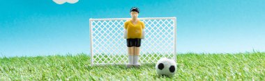 panoramic shot of toy goalkeeper near gates and ball on blue background, sports betting concept clipart