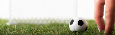Oyuncak futbol topunun yanındaki kadın parmakları ve beyaz spor bahisleri konseptine izole edilmiş futbol kapıları.
