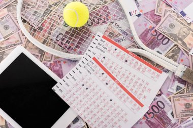 Dijital tabletin üst görünümü, bahis listeleri, tenis raketi ve top Euro ve dolar banknotları, spor bahisleri konsepti