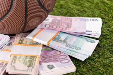 Beyzbol topunun neredeyse dolar ve euro banknotlarının yeşil çimlere yakın görüntüsü, spor bahisleri konsepti