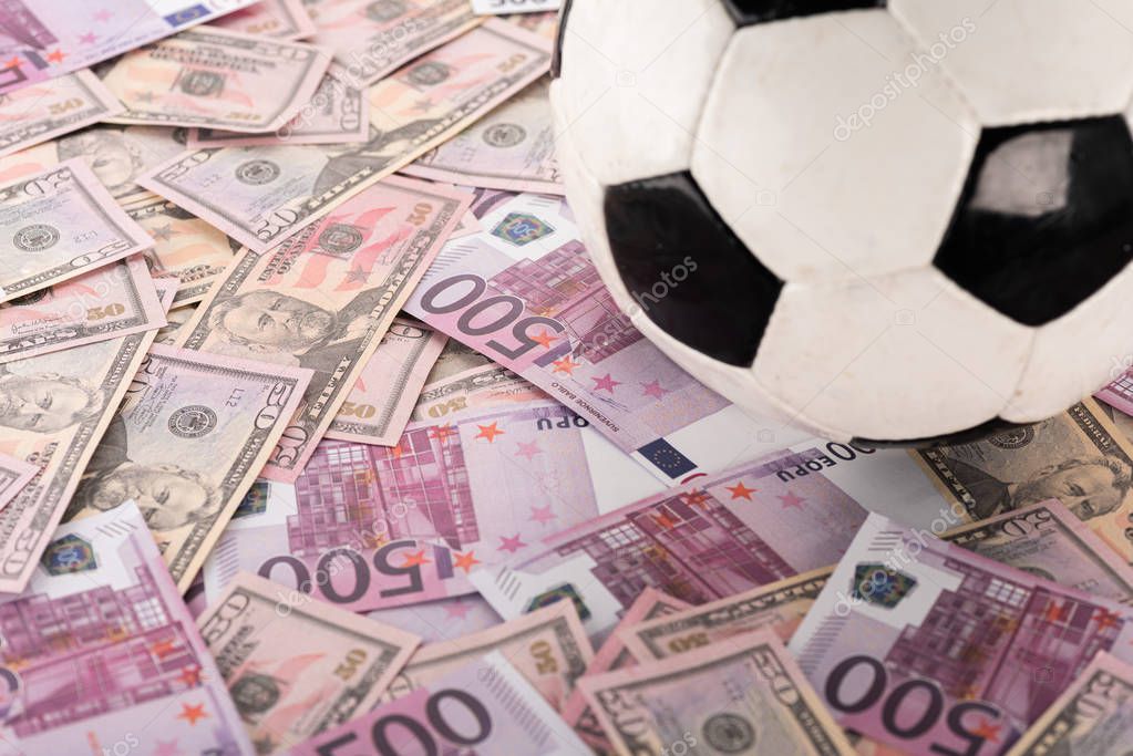 Close up view of soccer ball on euro and dollar banknotes, sports betting concept