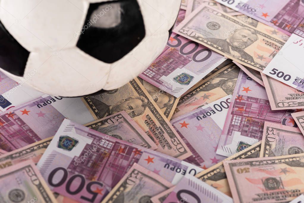 Close up view of soccer ball on euro and dollar banknotes, sports betting concept