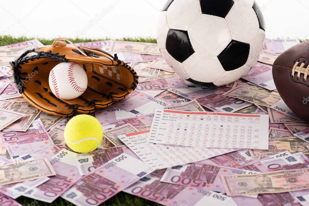 baseball glove and ball, soccer, tennis and rugby balls near betting lists on euro and dollar banknotes isolated on white, sports betting concept
