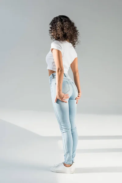 Rückansicht einer Frau in engen blauen Jeans auf grauem Hintergrund — Stockfoto