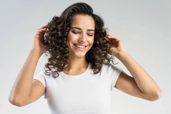 Allegra ragazza con i capelli ricci sorridente isolato su grigio — Foto stock