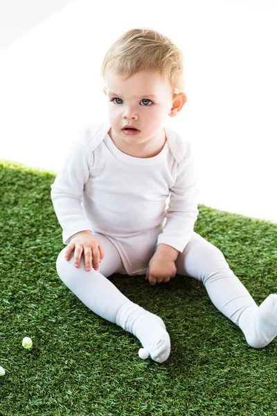 Adorable bébé blond assis sur herbe verte isolé sur blanc — Photo de stock