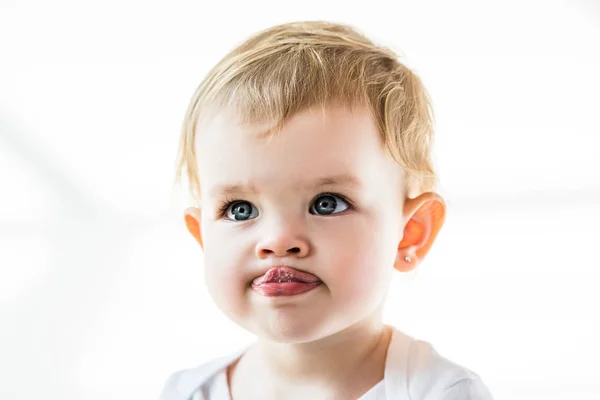 Adorable child with blonde hair showing tongue isolated on white — Stock Photo