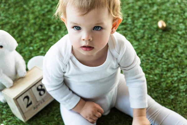 Adorable enfant assis près du calendrier en bois avec 28 Avril date et lapin décoratif — Photo de stock