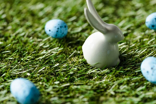 Selective focus of decorative rabbit and blue quail eggs on green grass surface — Stock Photo