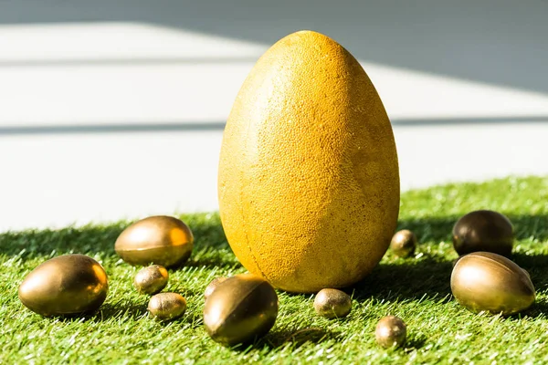 Huevo de avestruz amarillo y huevos de pollo y codorniz dorados en la superficie de hierba verde - foto de stock