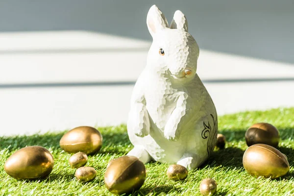 Decorativo conejo de Pascua final brillante huevos de oro en la superficie de hierba verde - foto de stock