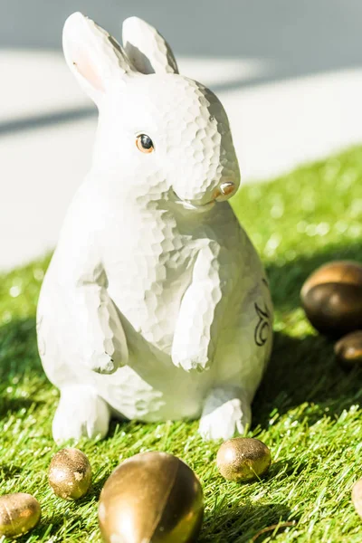 Foco selectivo de conejo de Pascua decorativa final brillante huevos de Pascua en la superficie de hierba verde - foto de stock