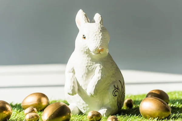 Coelho de Páscoa fim brilhante dourado ovos de Páscoa na superfície de grama verde — Fotografia de Stock