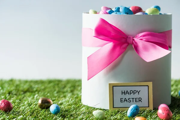 Confezione regalo con fiocco rosa pieno di uova di Pasqua multicolore isolate su bianco — Foto stock