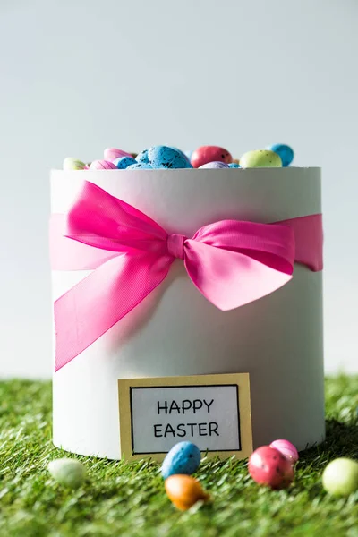 Gift box with pink bow full of colorful quail eggs isolated on grey — Stock Photo