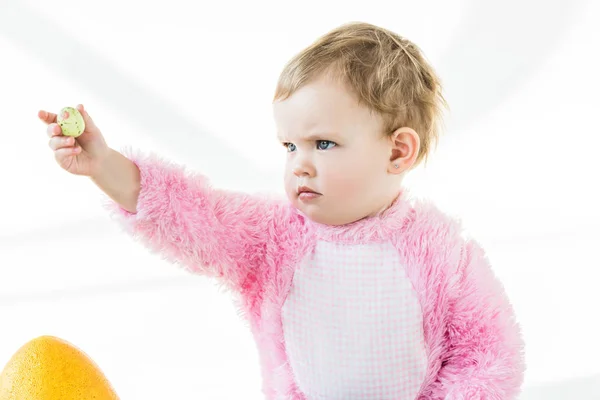 Entzückendes Baby mit buntem Wachtelei in ausgestreckter Hand isoliert auf weiß — Stockfoto