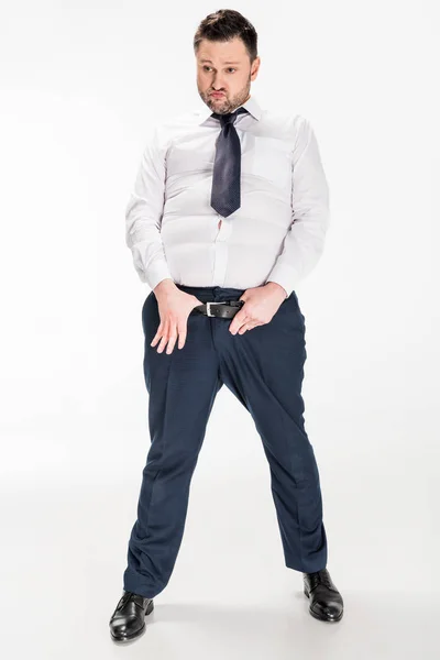 Overweight man in tight formal wear with hands on belt posing on white — Stock Photo