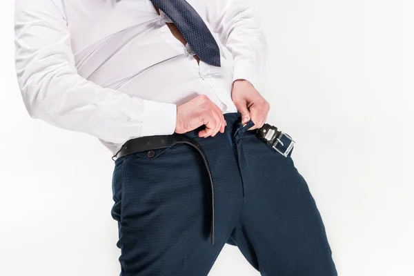 Vista recortada del hombre con sobrepeso en ropa formal poniéndose pantalones ajustados aislados en blanco - foto de stock