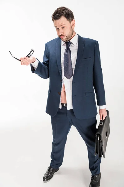 Overweight businessman in tight formal wear with briefcase holding glasses on white — Stock Photo