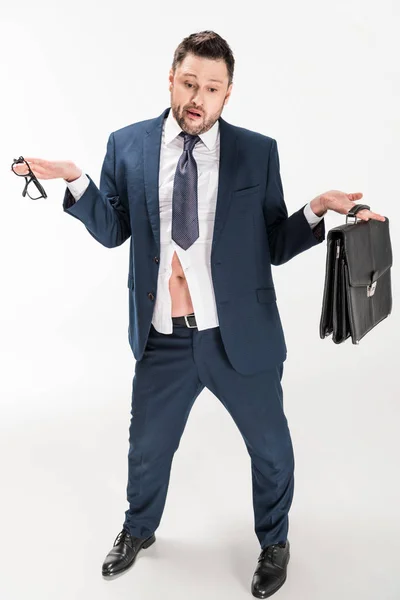 Overweight businessman in tight formal wear with briefcase and glasses doing shrug gesture on white — Stock Photo