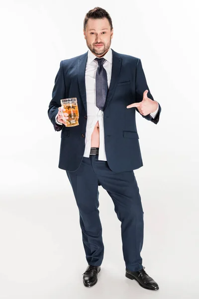 Hombre con sobrepeso en ropa formal apuntando con el dedo al vaso de cerveza en blanco - foto de stock