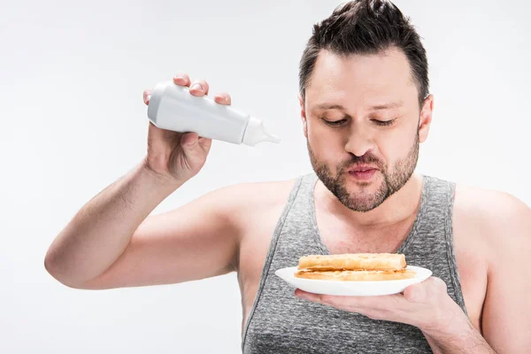 Molliger Mann mit Flasche Sirup und Waffeln auf weiß — Stockfoto