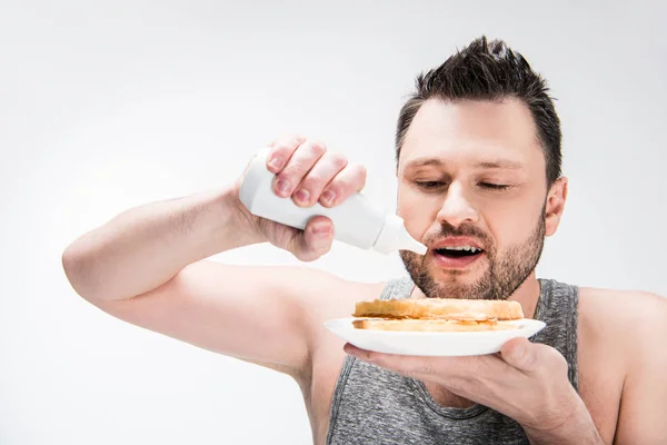 Chubby man pouring chocolate syrup on waffles isolated on white — Stock Photo
