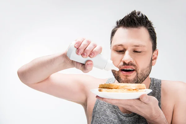 Gordito hombre verter el jarabe de chocolate en gofres aislados en blanco - foto de stock