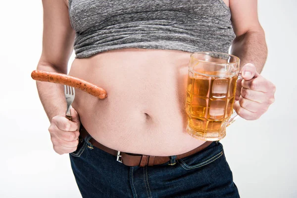 Cropped view of overweight man showing belly and holding glass of beer with grilled sausage isolated on white — Stock Photo